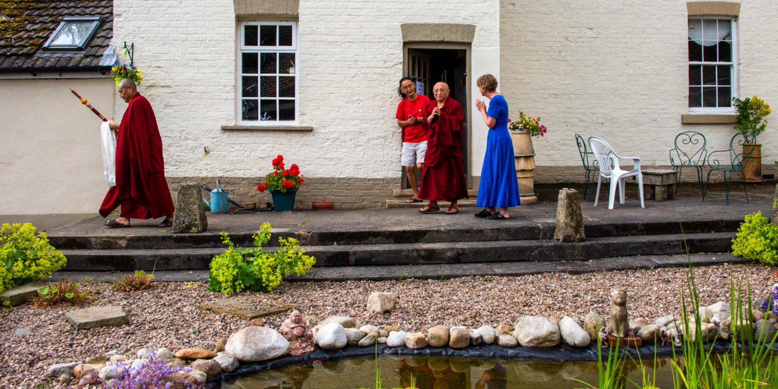 Buddhist monks and lay people next to an Edwardian building