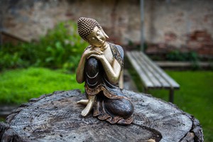 Buddha statue sitting with head leaning on raised legs.