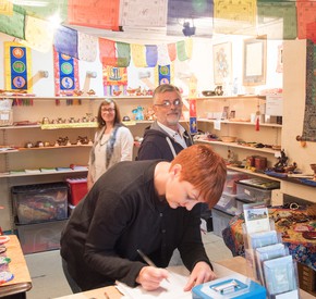 Buddhist volunteer Emma White in the shop with dharma items together with two customers.