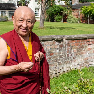Chokyi Nyima Rinpoche next to an old wall at Lindholme Hall