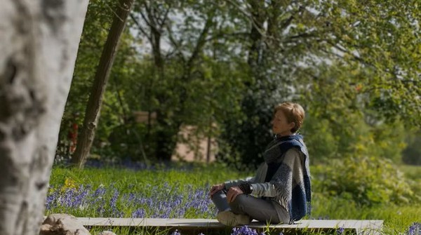 Buddhist meditation outdoors Woman meditating in a field of bluebells, UK.