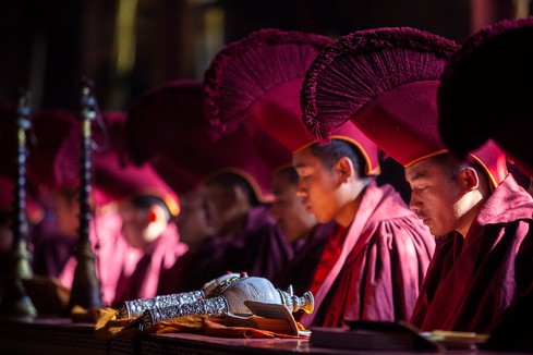Buddhist monks in traditional robes meditating in monastery in Nepal.