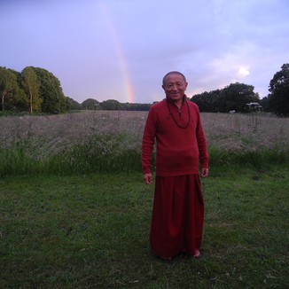 Chokyi Nyima Rinpoche posing in front of a rainbow