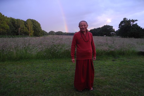 Chokyi Nyima Rinpoche posing in front of a rainbow