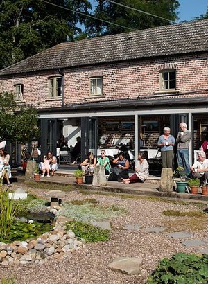 Group of people around a conservatory at the Community Cafe of Buddhist Retreat and Meditation Centre Gomde UK.