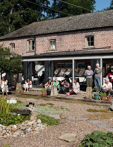 Group of people around a conservatory at the Community Cafe of Buddhist Retreat and Meditation Centre Gomde UK.