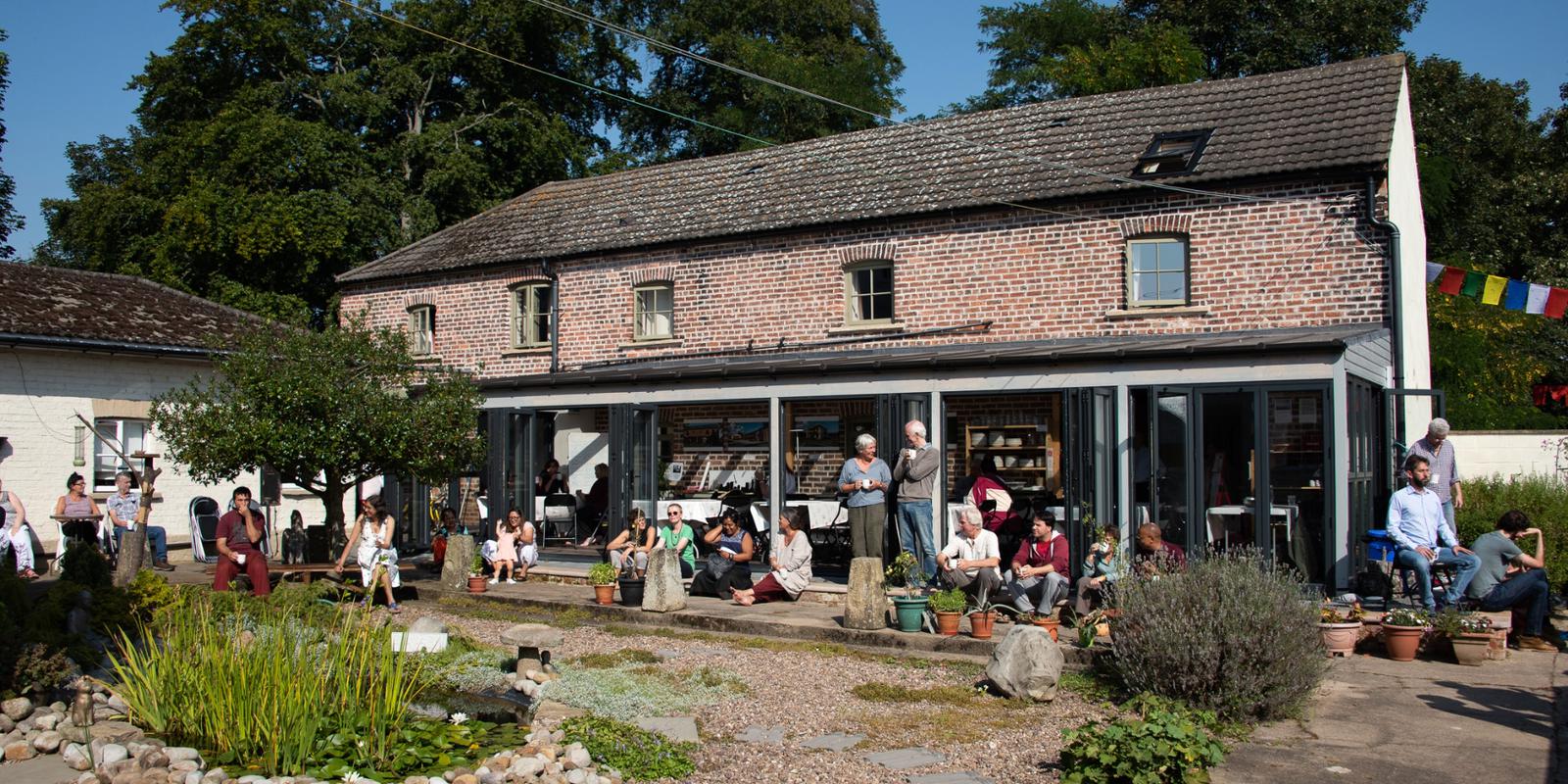 Group of people chatting and having tea at the central courtyard of Gomde UK
