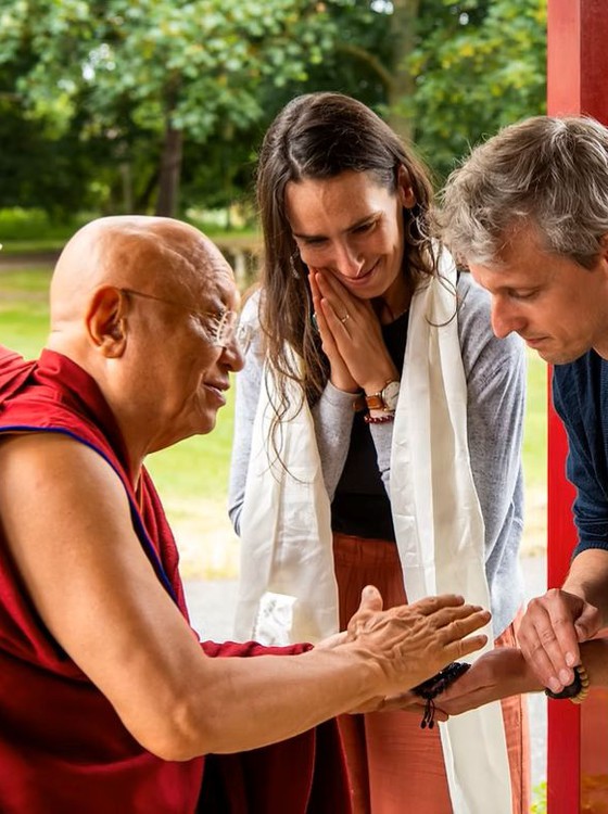 Man and woman giving an offering to Buddhist meditation master.Chokyi Nyima Rinpoche.