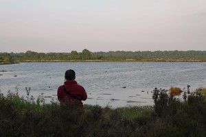 Khenpo Tokpa Tibetan Buddhist monk looking out over a serene lake.