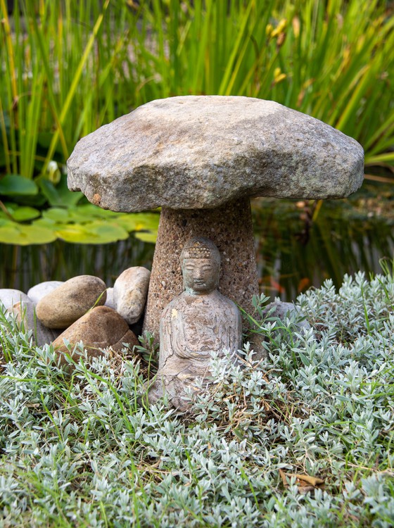 Buddha statue in a green garden underneath a stone cover