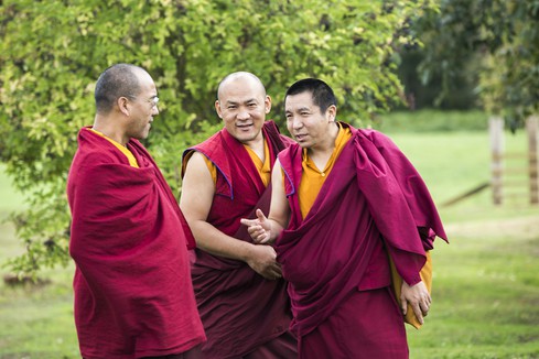 Three Tibetan Buddhist monks chatting in the sunshine.