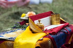Photograph of a pecha text with flowers and brocade, taken outdoors with a short depth of field.